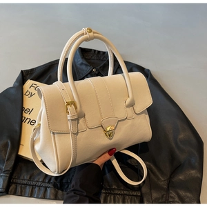 Detail of cream PU leather handbag with golden clasp on vintage books and leather