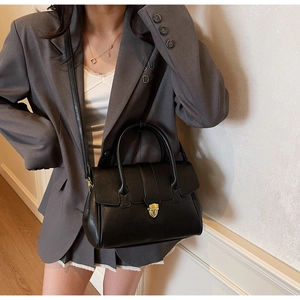 Detail of a black leather briefcase with vintage gold buckle and semi-circular flap