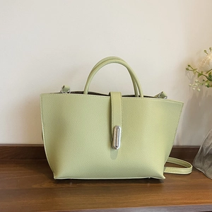 Pistachio green litchi grain leather tote bag with silver buckle in a minimalist setting
