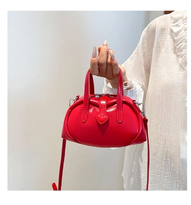 Detail of red shell-shaped handbag with heart clasp and detachable shoulder strap