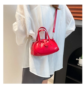 Detailed close-up of a glossy red heart handbag with silver metal buckle on white shirt