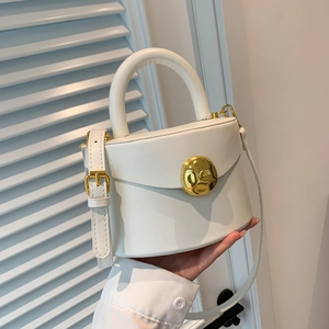 Minimalist white leather handbag with a round gold buckle and versatile strap in a lifestyle set