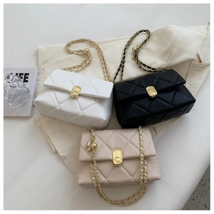 Three quilted chain bags in white, black and beige displayed on a white blazer
