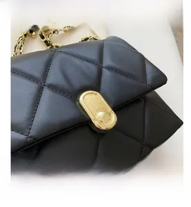 Detail of black quilted leather shoulder bag with gold metal twist lock and chain strap
