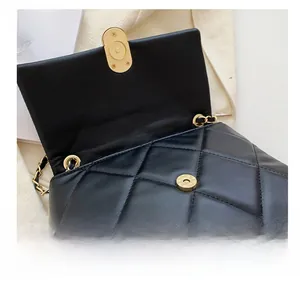 Detailed view of the golden magnetic buckle and quilted leather on a chain bag