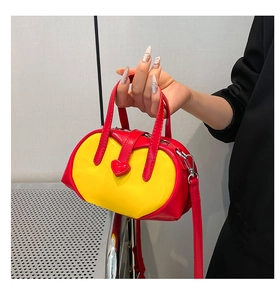 Detail of red and yellow heart-shaped handbag with glossy finish and dual straps