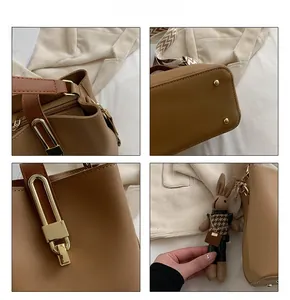 Detail view of caramel brown bucket bag with gold hardware, woven strap and bunny charm