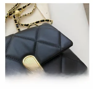 Detail shot of black quilted faux leather handbag with gold chain strap and metal lock
