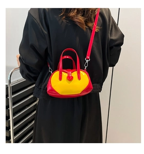 Detail of red and yellow heart-shaped patent leather crossbody bag with silver hardware