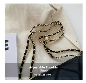 Detail of adjustable golden chain shoulder strap on black quilted leather crossbody bag