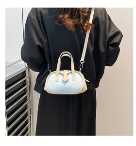 Detail of light blue shell bag with heart ornament shown on model back
