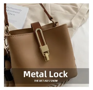 Detailed close-up of brown leather bucket bag with a polished golden metal lock buckle