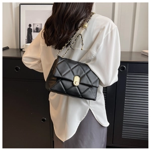 Detail of black quilted leather bag with gold chain and spherical adjustment buckle