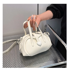 Detail view of mini cylinder handbag with heart decorative strap and silver metal hardware