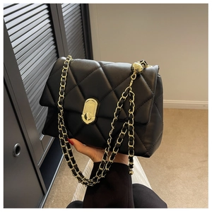 Detail of quilted leather shoulder bag featuring gold chain strap and metal adjustment ball