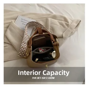 Detail view of the brown bucket bag interior capacity and the woven shoulder strap