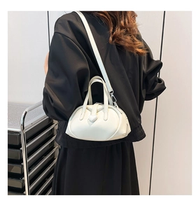 Detailed view of the creamy white heart-buckle mini bag on a minimalist shelf