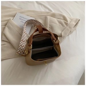 Top view of brown bucket bag showing interior zip compartment and wide woven strap