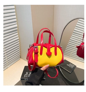Detail of a glossy yellow and red handbag with a heart-shaped clasp on a vanity table