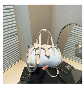 Detailed close-up of heart-shaped clasp on a mini pastel blue and white leather shell bag