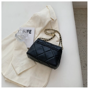 Detail of black quilted leather shoulder bag with vintage gold chain strap and texture