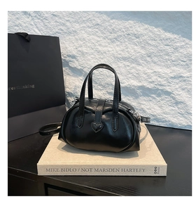 Detail of black heart-shaped handbag with glossy leather finish and adjustable strap