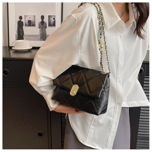 Detail of black quilted leather bag with gold metal chain strap and turn-lock closure