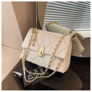 Detailed view of white quilted leather chain bag with gold hardware and ball adjuster