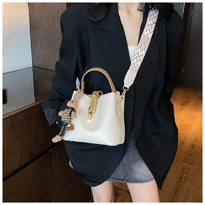 Detailed view of cream leather bucket bag with geometric wide strap and bunny charm