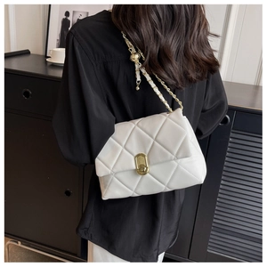 Close-up of white quilted chain bag with gold rotating lock on a shoulder model