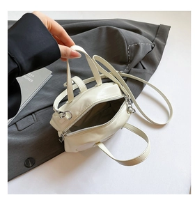 Overhead view of small cream shell bag on grey suit blazer with fashion magazine