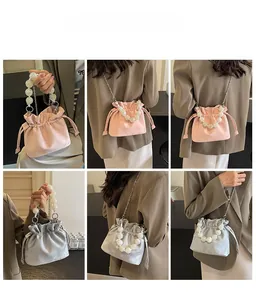 Detail view of pink and grey satin bucket bags with large pearl handles and chain straps