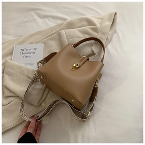 Close-up of bucket bag featuring a gold metal buckle and geometric woven wide strap