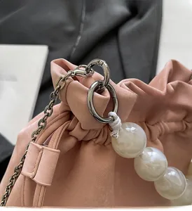 Detail of pink drawstring bag showing silver hardware and white marble bead decoration
