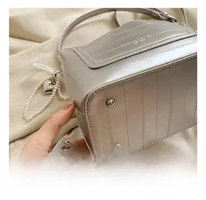 Detail shot of silver bucket bag base with protective studs and heart pearl chain