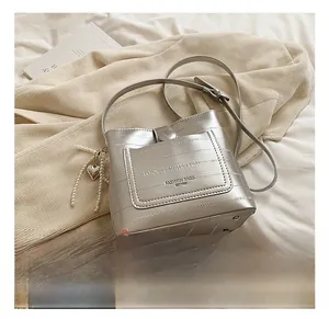 Silver leather bucket bag detail with pearl chain and heart pendant on white fabric