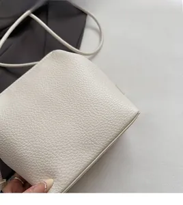 Close-up detail of beige lychee texture synthetic leather on a minimalist square bag