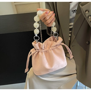 Detail of pink drawstring bucket bag with marble bead handle and metallic chain accents