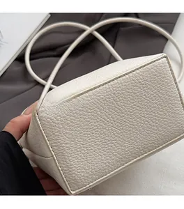 Close-up of white lychee grain leather bag showing detailed black stitching craftsmanship