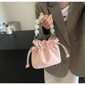 Detail of pink drawstring bucket bag featuring pearl handle and silver chain strap
