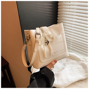 Close-up of white bucket bag featuring crocodile pattern leather and pearl bow detail