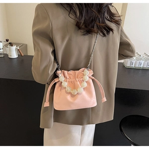 Pink drawstring bucket bag with beaded handle and silver chain strap on model back
