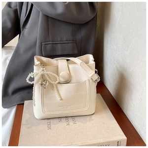 Detail of crocodile pattern leather bucket bag with pearl bow and silver heart pendant