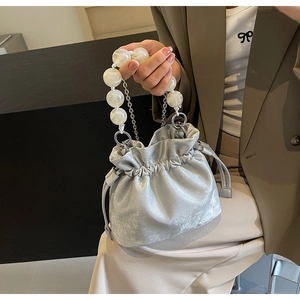 Detail of silver drawstring bucket bag with large marble-textured beaded handle and metallic fabric
