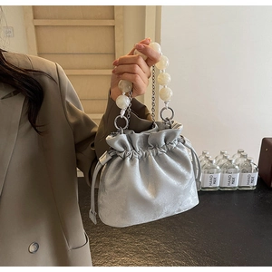 Detailed view of silver drawstring bag with oversized pearl beads and metallic chain