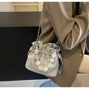 Detail of silver drawstring bucket bag with marble bead handle and metallic satin finish
