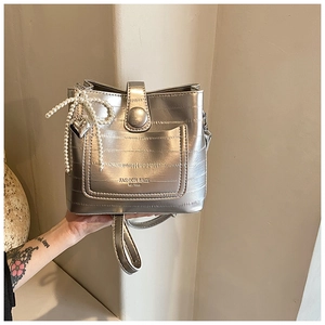 Close-up of metallic silver bucket bag with pearl heart charm and textured finish