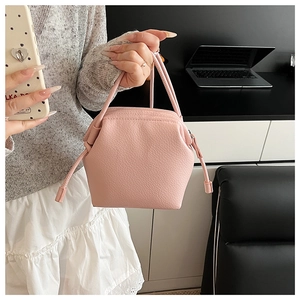 Detail of pink PU leather handbag with pebble texture and dual handles in a modern setting