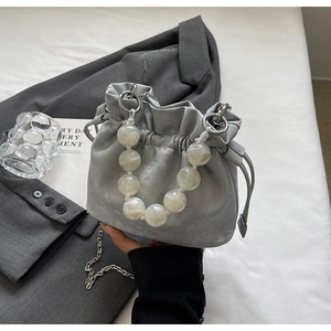 Close-up of silver-grey silk texture bucket bag with chunky white pearl handle