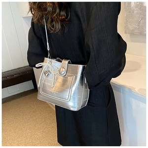 Detail of silver crocodile texture bag with pearl bow and heart metal pendant